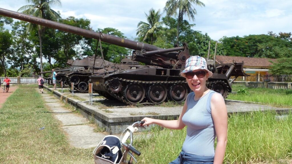 Paola Bertoni in bici davanti a un carro armato, dintorni di Ho Chi Minh City, Vietnam