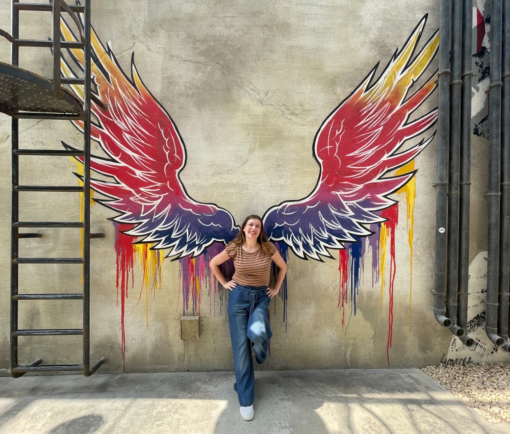 Paola Bertoni nel quartire La Mer di Dubai davanti a un murale con le ali