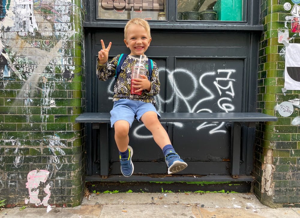 Figlio di Paola Bertoni beve un centrifugato di frutta a Brick Lane, Londra