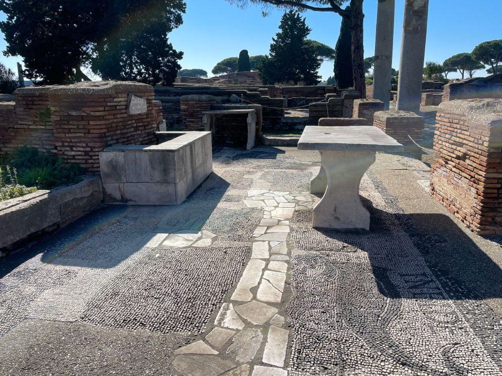 Interno della pescheria di Ostia Antica con il mosaico del delfino e la scritta "Imbide calco te"