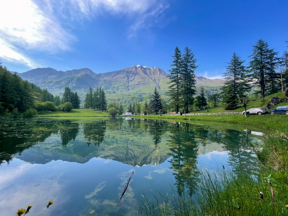 Il Lago di Laux con camper posteggiato il libera sullo sfondo, nel parcheggio delle autovetture