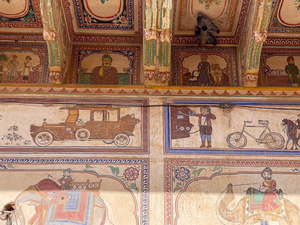 Auto, telefono e biciclette portati dai colonialisti britannici affrescati sulla facciata del Banshidhar Haveli a Mandawa