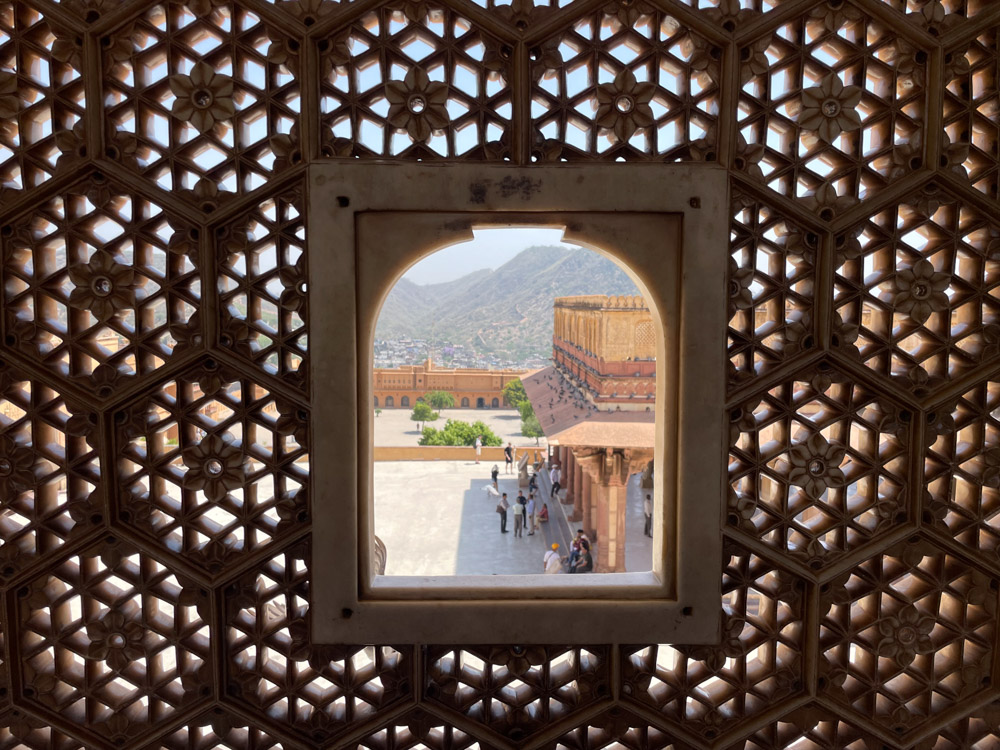 Finestrella con muri in pietra finemente lavorati all'Amber Fort di Jaipur