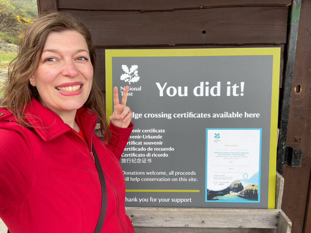 Paola Bertoni davanti al cartello del certificato di attraversamento del ponte di corda Carrick-a-Rede