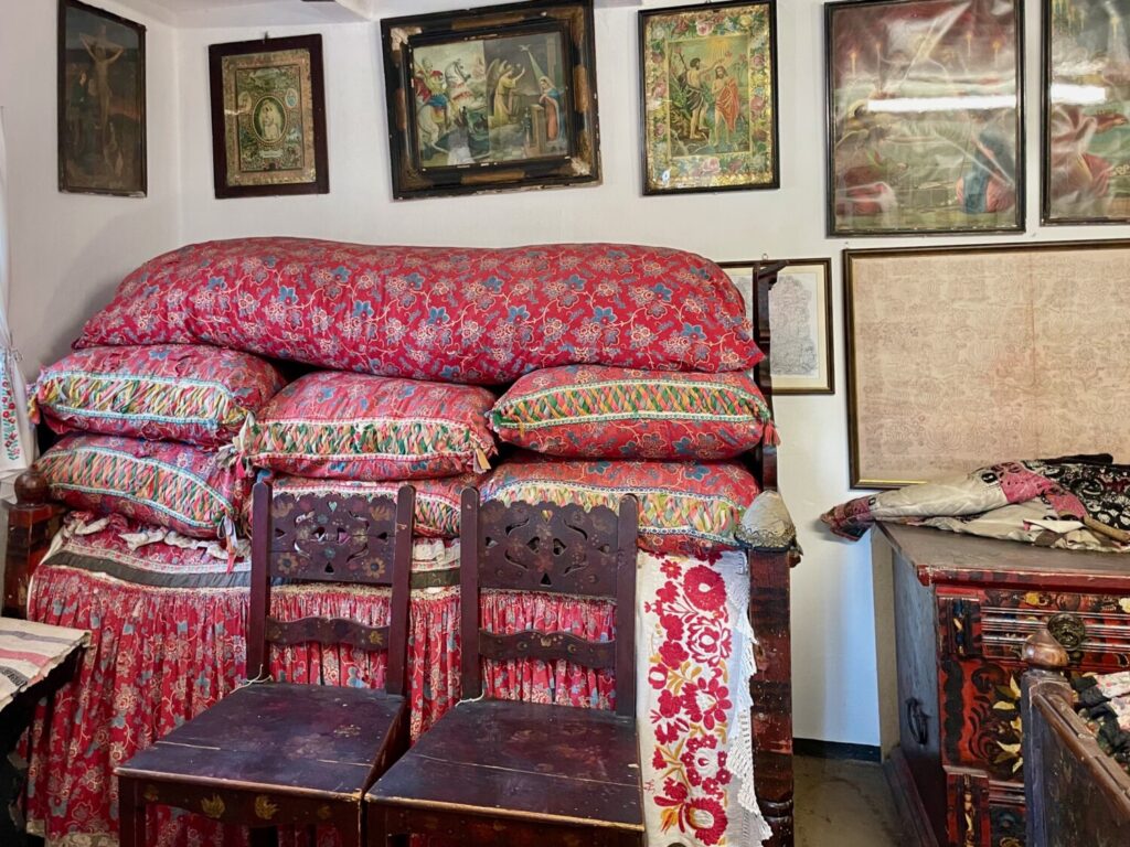 Interno della casa di Bori Kisjankó, con il letto alto simbolo di ricchezza e immagini religiose, a Mezőkövesd