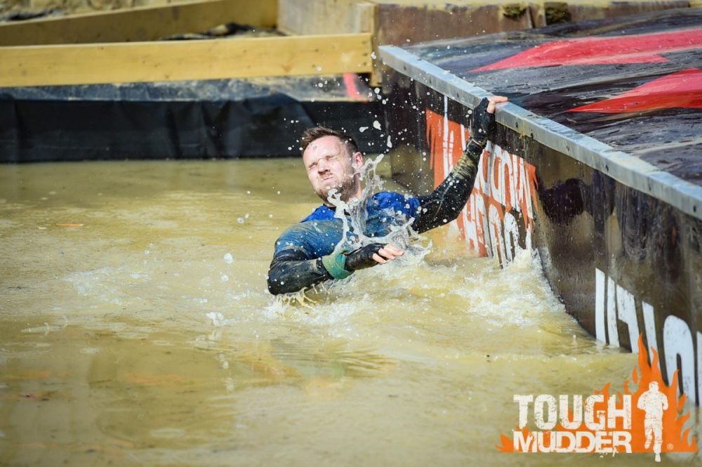Partecipante che cerca di superare un ostacolo della Tough Mudder, foto Tough Mudder UK