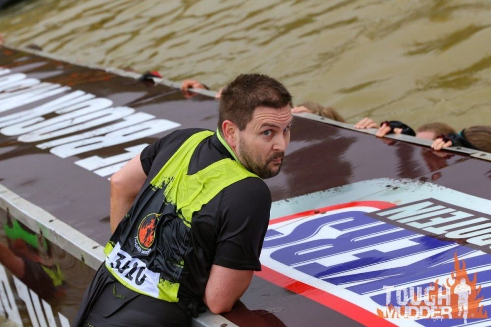 Partecipante che cerca di superare un ostacolo della Tough Mudder, foto Tough Mudder UK