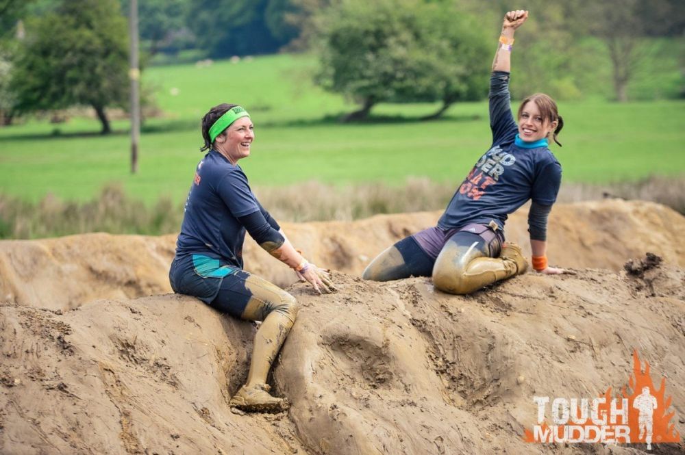 Partecipanti felici di aver scalato una montagna di fango alla Tough Mudder, foto Tough Mudder UK